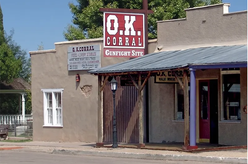 The O.K. Corral Gunfight Site — Tombstone, Arizona The entrance to the O.K. Corral gunfight site, an adobe building with a covered porch and vintage livery signage, in Tombstone, Arizona.